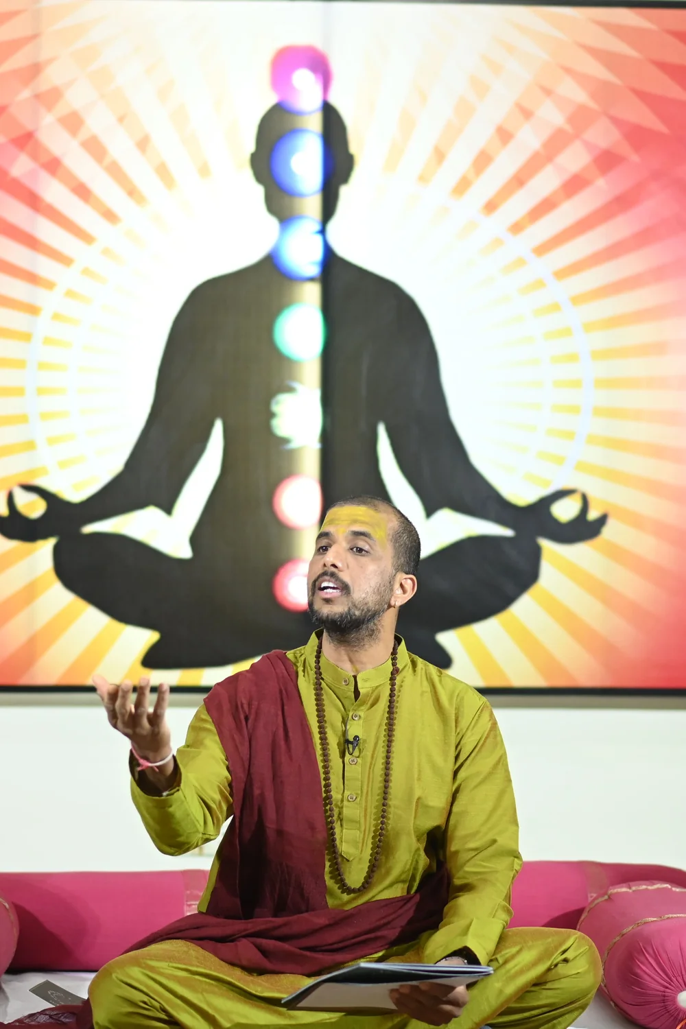 Ashishh L Vyas leading a session in front of a chakra backdrop